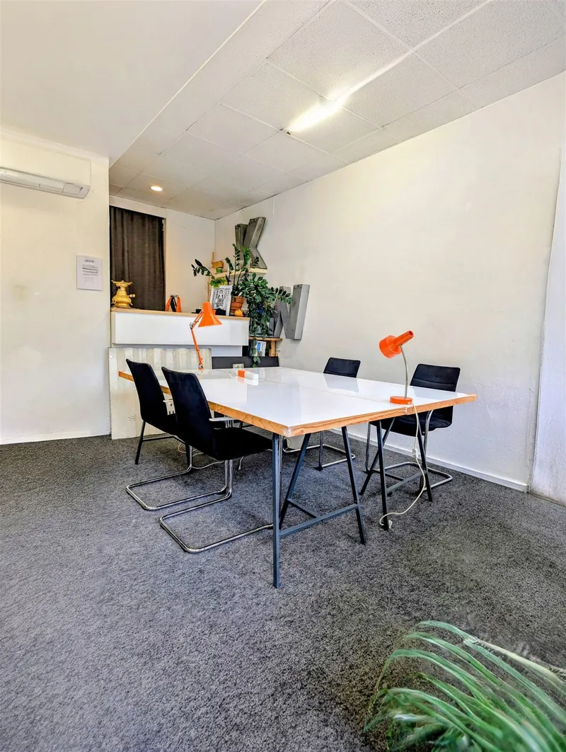 Shared table with black chairs next to the kitchen area in the KOTTIWORX coworking space