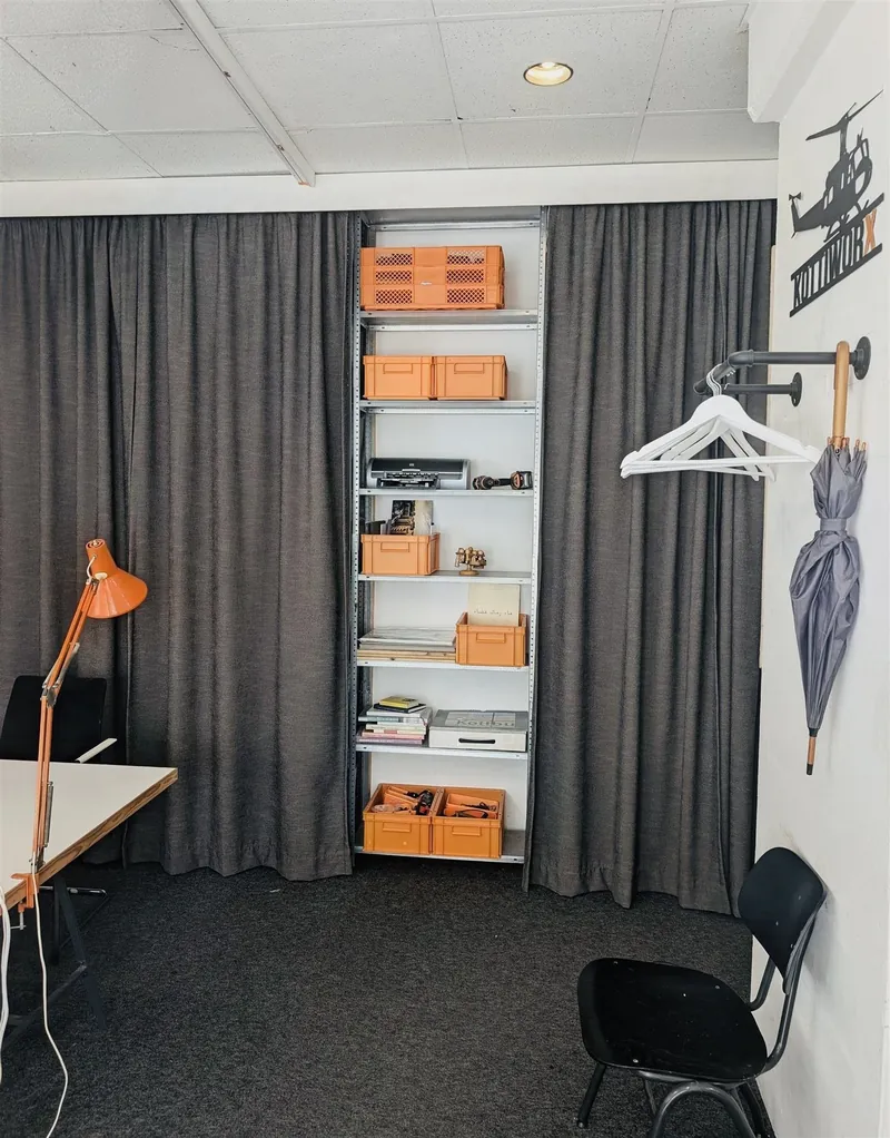 Shelf storage space with orange boxes and a coat rack for coworkers