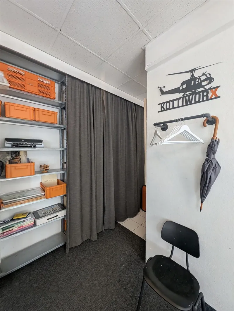 Open shelving with orange storage boxes and a KOTTIWORX wall sign