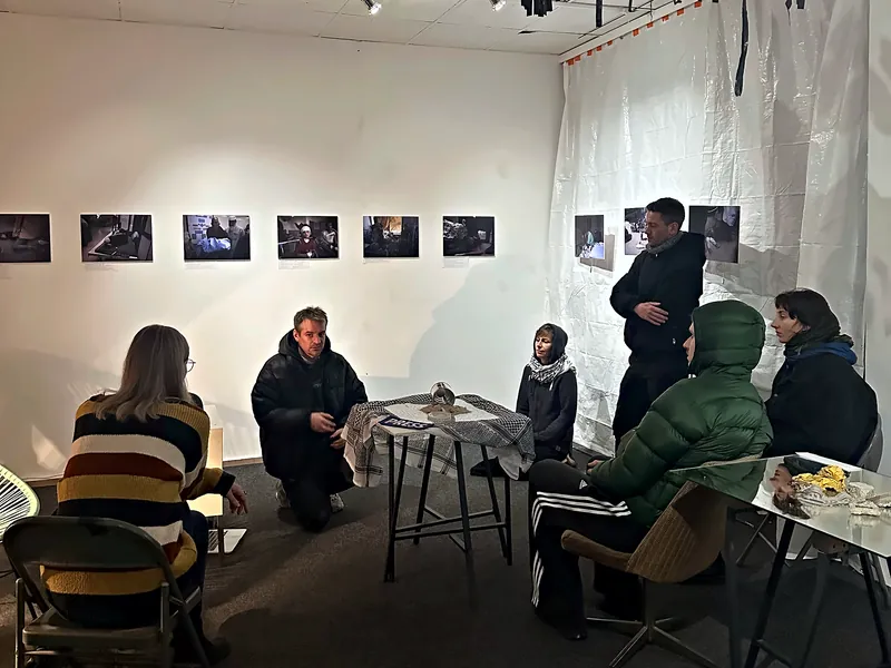 Evening talk at a photo exhibition in the KOTTIWORX event space, Berlin-Kreuzberg – small group seated in front of the photographs