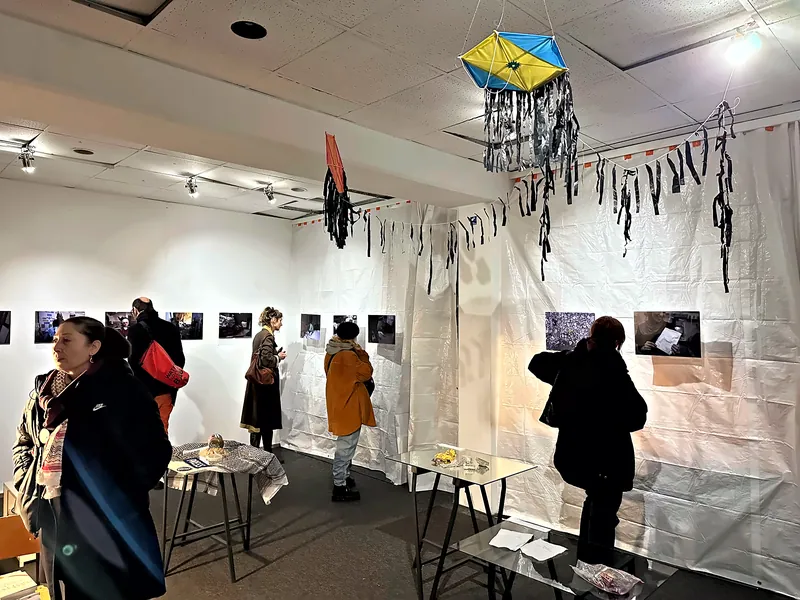 Visitors viewing a photo exhibition in the KOTTIWORX event space, Berlin-Kreuzberg, with hanging kite installations