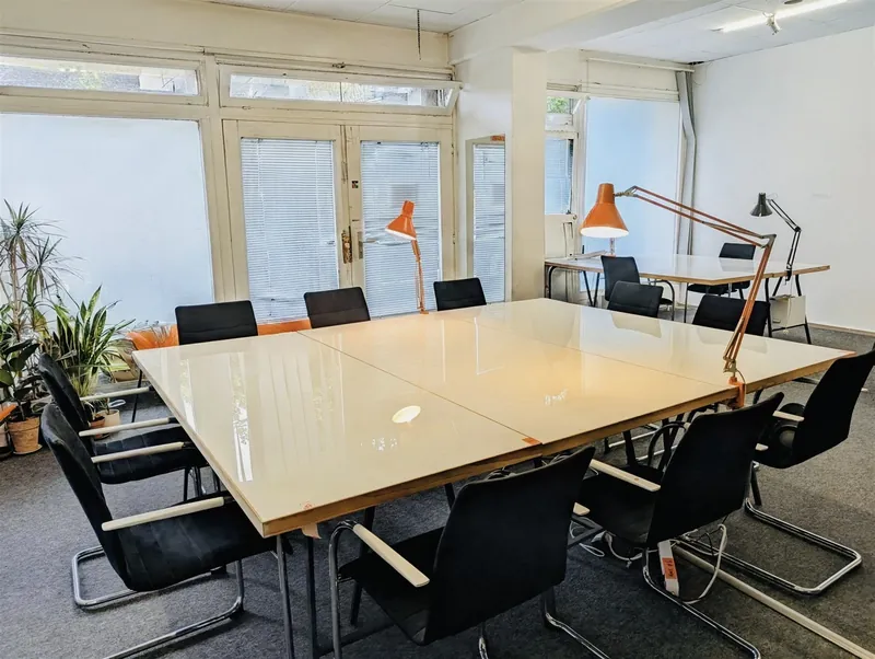 Large meeting table with black chairs, set up for a workshop or meeting in the event space