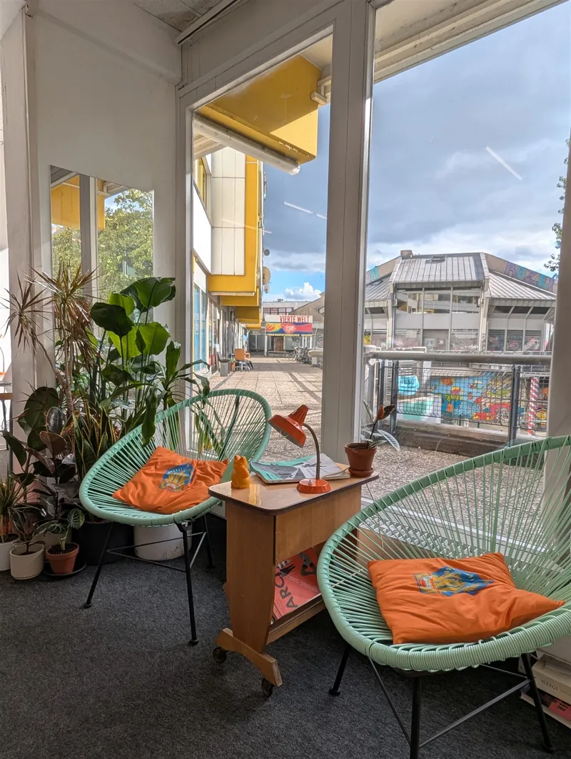 Lounge corner with green woven armchairs and plants by a sunny window